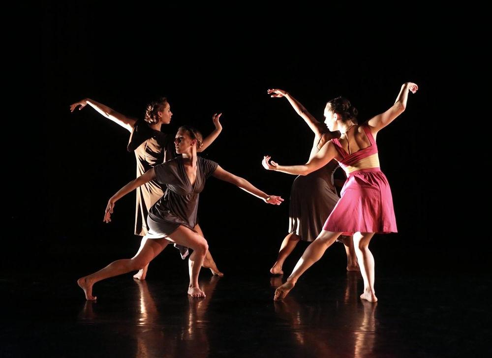 Four dancers perform on stage in a circle.